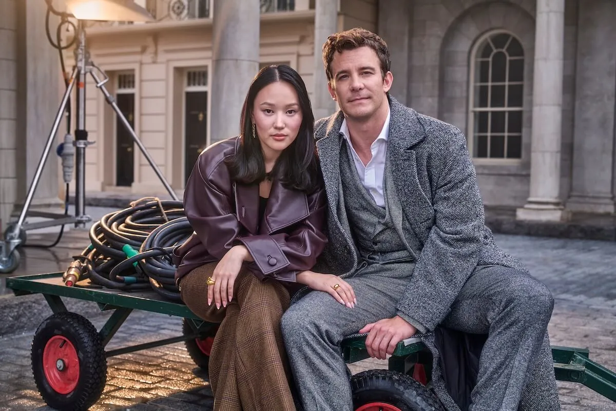 Yerin Ha and Luke Thompson sitting next to each other on the set of 'Bridgerton' Season 4