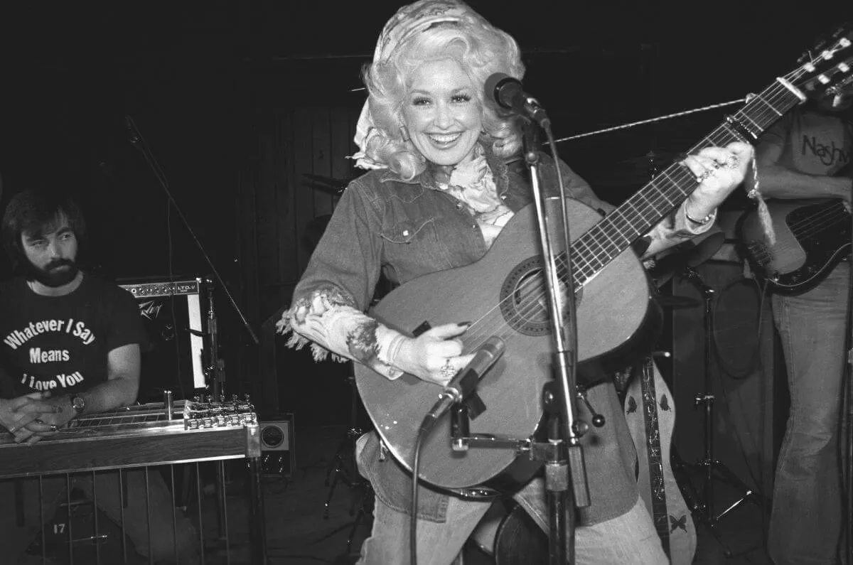 A black and white picture of Dolly Parton playing guitar at New York's Bottom Line.