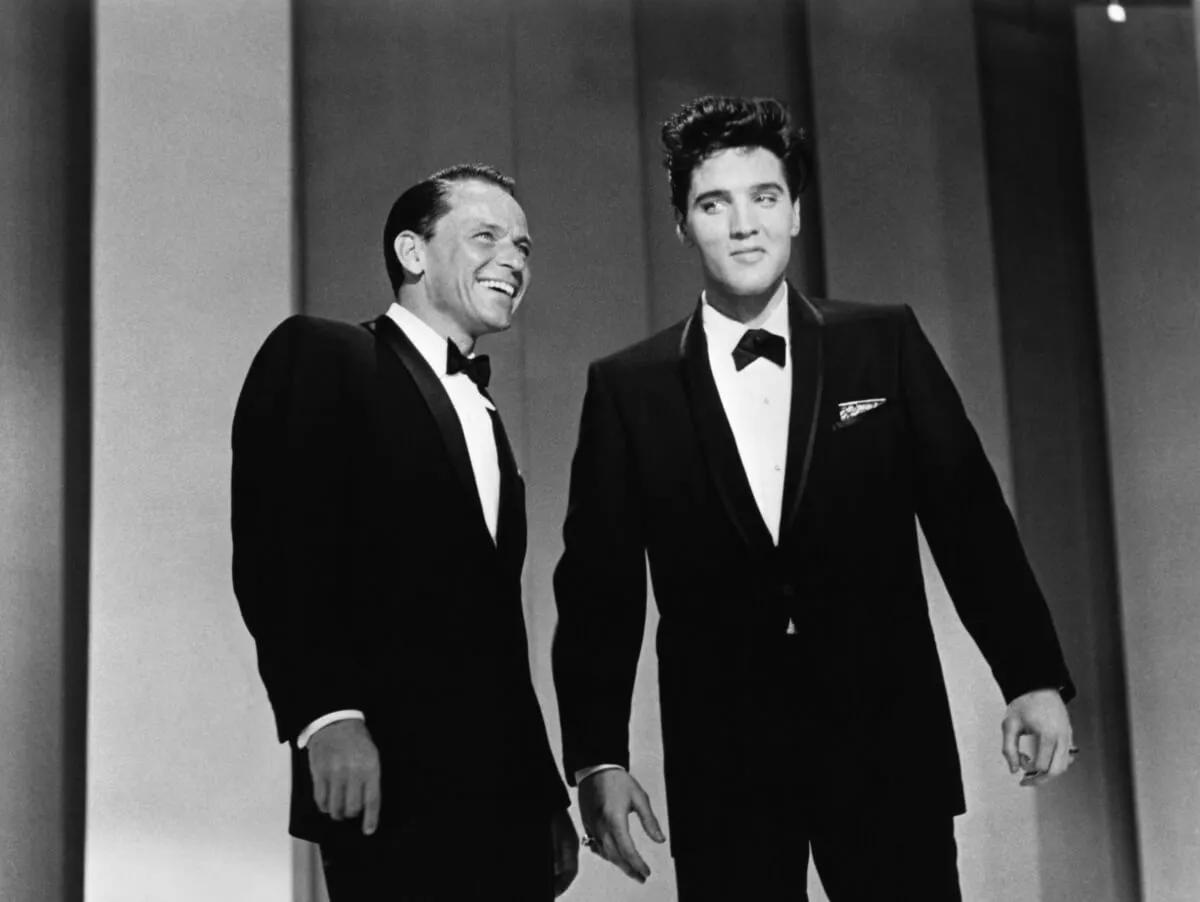 A black and white picture of Frank Sinatra and Elvis Presley standing together. They wear tuxedos.