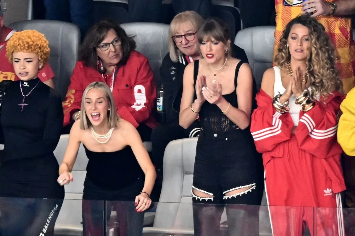 Taylor Swift standing and clapping in her Super Bowl suite in 2024. She's with Blake Lively and Donna Kelce. 